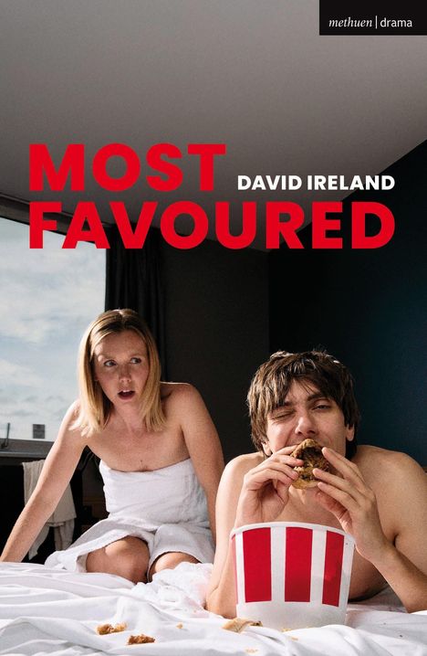 Text: "MOST FAVOURED" und "DAVID IRELAND". Eine Frau und ein Mann in Handtüchern auf einem Bett, Mann isst Hähnchen aus einem Eimer.
