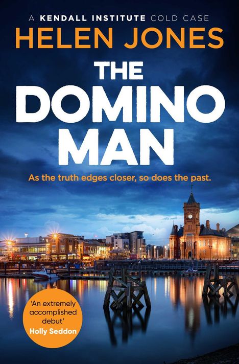 Text: "A Kendall Institute Cold Case", "Helen Jones", "The Domino Man", "As the truth edges closer, so does the past." Es zeigt eine beleuchtete Küstenstadt in der Dämmerung mit einem markanten Uhrturm.