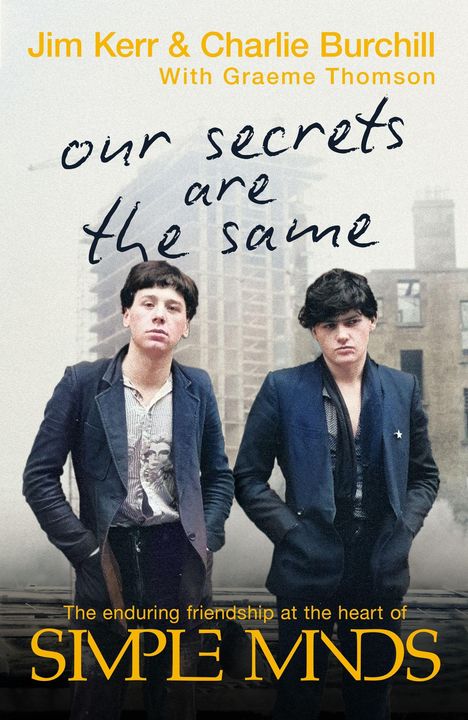 Text: „Jim Kerr & Charlie Burchill“, „our secrets are the same“, „SIMPLE MINDS“. Zwei Männer in Anzügen, urbaner Hintergrund.