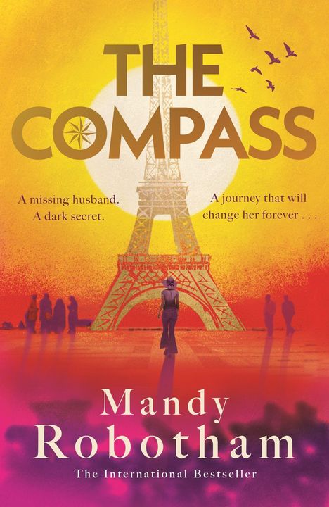 Text: "THE COMPASS. A missing husband. A dark secret. A journey that will change her forever. Mandy Robotham. The International Bestseller."

Illustration: Eiffelturm bei Sonnenuntergang, Menschen im Vordergrund.
