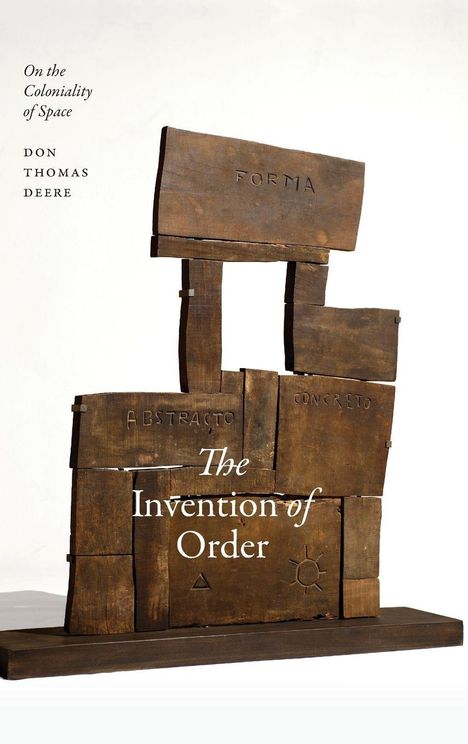 Buchcover mit Texten: "On the Coloniality of Space", "Don Thomas Deere", "The Invention of Order". Holzskulptur im Fokus.