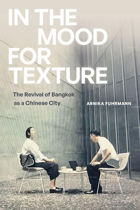 Großer Text: "IN THE MOOD FOR TEXTURE". Zwei sitzende Personen an einem runden Tisch in einem grauen, modernen Raum.