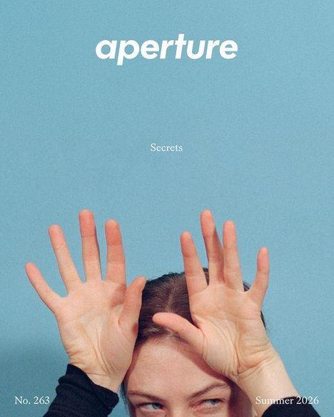 „aperture“, „Secrets“, „No. 263“, „Summer 2026“. Ein Gesicht mit hochgehobenen Händen vor blauem Hintergrund.