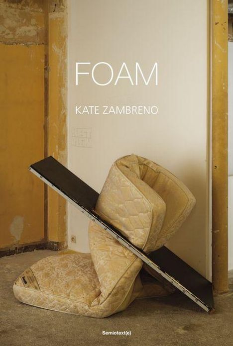 „FOAM“ von Kate Zambreno. Zwei Matratzen und ein Brett lehnen chaotisch an einer Wand in einem kahlen Raum.