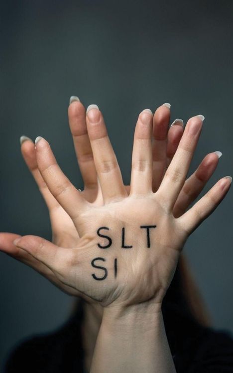 Auf zwei Händen stehen die Buchstaben "SLT" und "SI". Die Hände sind übereinander gelegt.