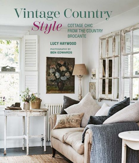 "Vintage Country Style" in großen Buchstaben. Helles Wohnzimmer mit Sofa, Kissen, antiken Möbeln, Gemälde und Fenstern.