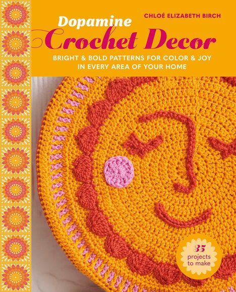 "Dopamine Crochet Decor" ist vorne in großen Buchstaben zu sehen. Darunter ein gehäkeltes fröhliches Gesicht in Orange und Pink.