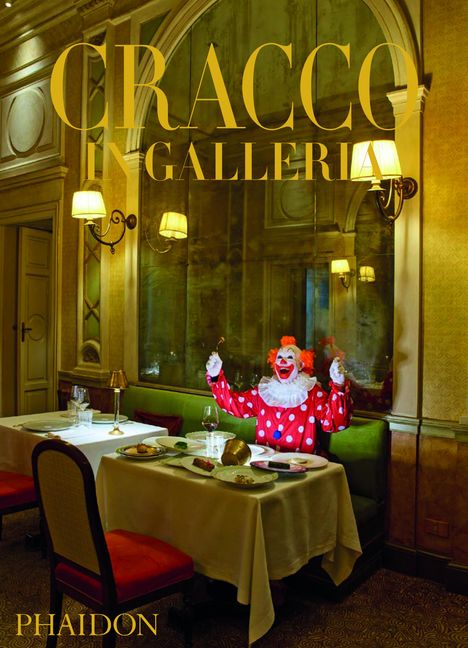 "CRACCO IN GALLERIA, PHAIDON." Ein Clown sitzt fröhlich an einem elegant gedeckten Tisch in einem stilvollen Restaurant.