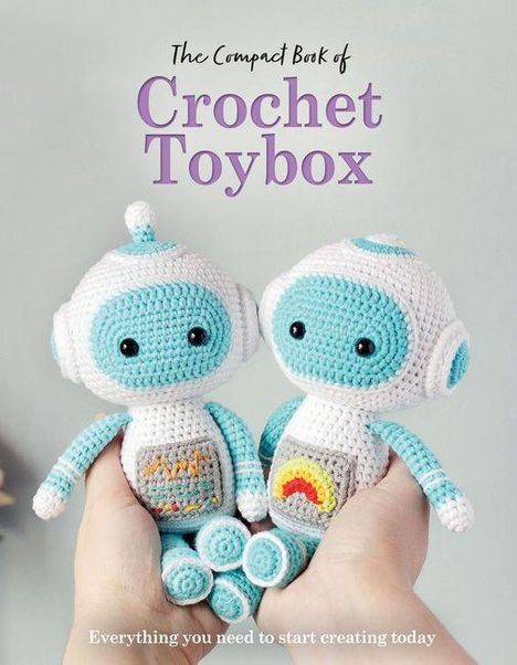 "The Compact Book of Crochet Toybox. Everything you need to start creating today." Zwei gehäkelte Roboter in Händen gehalten.