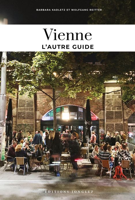 "Vienne: L’autre Guide" oben, "Éditions Jonglez" unten. Nachtaufnahme eines lebhaften Straßencafés, Bäume im Hintergrund.