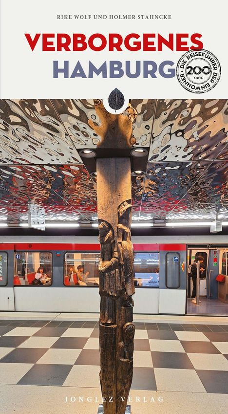 "Verborgene Hamburg", "Jonglez Verlag". Eine hölzerne Skulptur vor einer U-Bahn mit gemustertem Deckendekor.