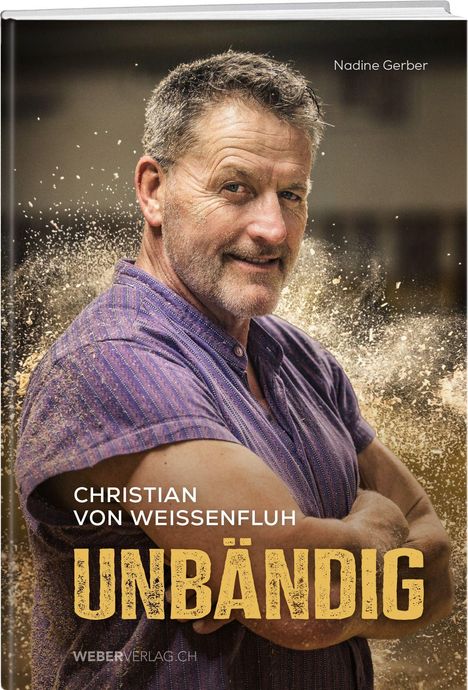 „Christian von Weissenfluh - Unbändig“ in weiß und gelb. Mann in lila Hemd, verschränkt die Arme, mit Sand umgeben.