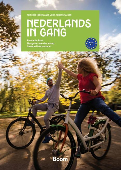 Text: "Nederlands in Gang". Zwei Personen geben sich auf Fahrrädern ein High-Five in einer herbstlichen Parkszene.