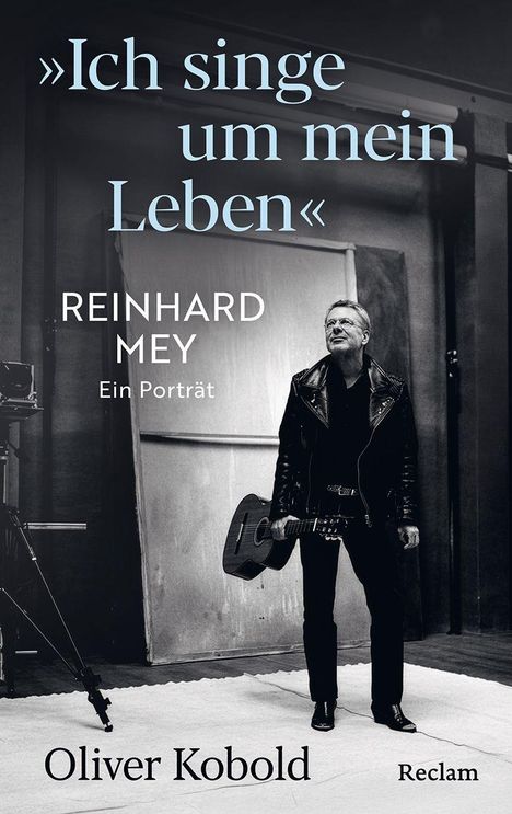 "Ich singe um mein Leben." Reinhard Mey, ein Porträt. Oliver Kobold. Schwarz-weiß Foto eines Mannes mit Gitarre.