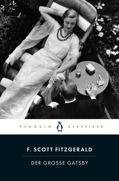 „PENGUIN KLASSIKER“. Frau auf Liegestuhl in Abendkleid, Mann hält ein Glas, edle Atmosphäre.