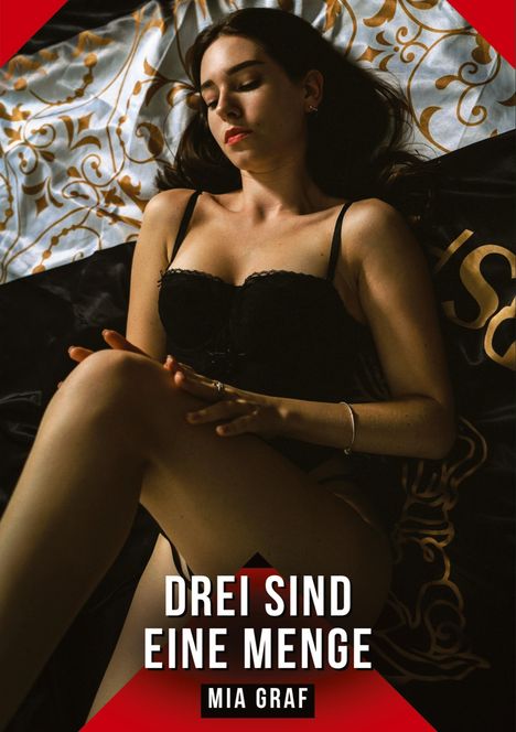"Drei sind eine Menge, Mia Graf." Eine Frau in schwarzer Unterwäsche liegt auf einem gemusterten Bettbezug.