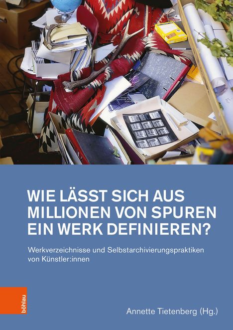 Wie lässt sich aus Millionen von Spuren ein Werk definieren? Unordentlicher Schreibtisch mit Papieren und rotem Tuch.