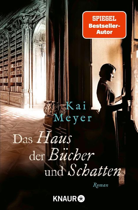 "SPIEGEL Bestseller-Autor. Kai Meyer. Das Haus der Bücher und Schatten. Roman. KNAUR. Frau steht vor Bücherregal in großem Raum."