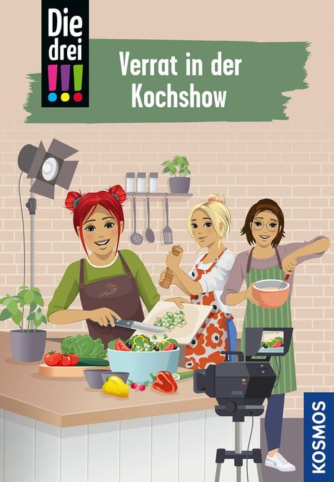 „Verrat in der Kochshow“ steht oben. Illustrierte Szene: Drei junge Frauen kochen gemeinsam mit Kamera und Zutaten.