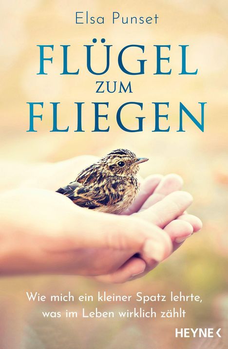 Titel: "Flügel zum Fliegen". Ein kleiner Spatz sitzt in einer ausgestreckten Hand, Hintergrund verschwommen.