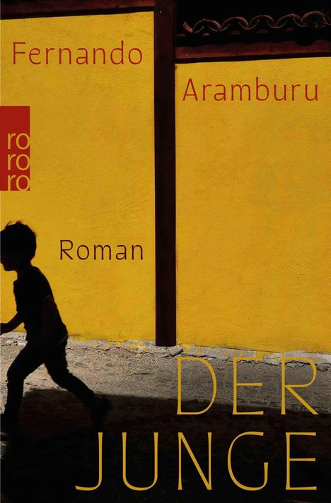 Text: "Fernando Aramburu, Roman, DER JUNGE". Ein Junge in Silhouette läuft vor einer gelben Mauer. Links ein rotes Logo.