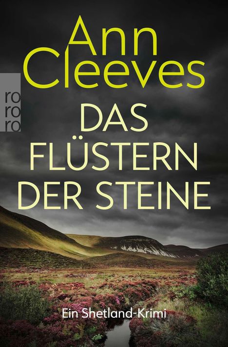 „Ann Cleeves, Das Flüstern der Steine, Ein Shetland-Krimi“. Landschaft mit Heidekraut und dramatischem Himmel.
