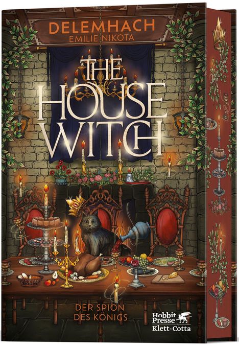 "The House Witch", oben. "Der Spion des Königs" unten. Ein opulenter Tisch mit Speisen, einer Katze, Kerzen und Pflanzen.