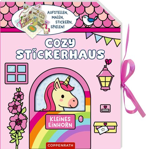 Text: "AUFSTELLEN, MALEN, STICKERN, SPIELEN!", "COZY STICKERHAUS", "KLEINES EINHORN". Ein Einhorn auf einer bunten Tür.