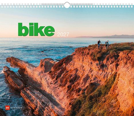 Text: "bike 2027". Zwei Radfahrer an einer Küste, die Sonne geht über dem Meer unter.