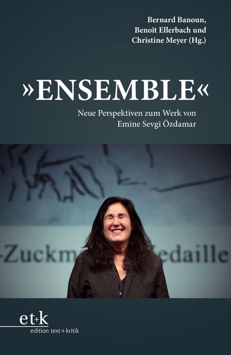 „ENSEMBLE“: Neue Perspektiven zum Werk von Emine Sevgi Özdamar. Lächelnde Frau vor unscharfem Hintergrund.