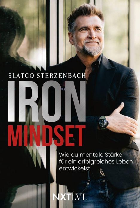 „Slatco Sterzenbach, Iron Mindset: Wie du mentale Stärke für ein erfolgreiches Leben entwickelst.“ Ein Mann lehnt lächelnd an einer Wand.