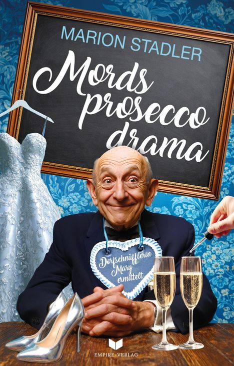 Ein älterer Mann mit einem Lebkuchenherz, darauf "Dorfschnüfflerin Mary ermittelt", zwei Sektgläser, ein Brautkleid.