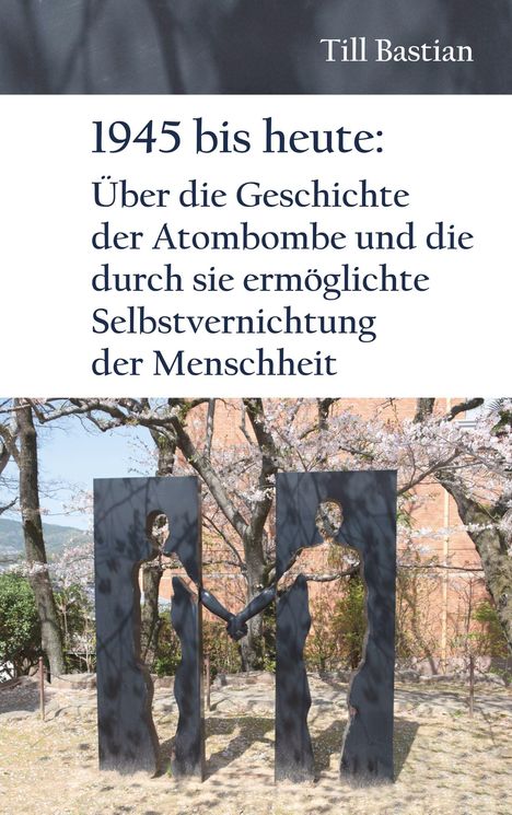 "1945 bis heute: Über die Geschichte der Atombombe..." Zwei Metall-Silhouetten, die sich die Hände reichen, vor Bäumen.