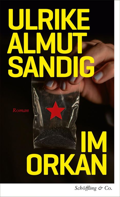 „ULRIKE ALMUT SANDIG IM ORKAN“, „Roman“ in Rot. Hand hält Tütchen mit rotem Stern und schwarzem Pulver.