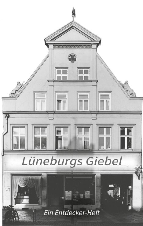 „Lüneburgs Giebel“ und „Ein Entdecker-Heft“ sind die Texte auf einer Hausfassade im traditionellen Architekturstil.