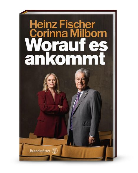 Text: Heinz Fischer, Corinna Milborn, Worauf es ankommt. Zwei Personen in einem Theatersaal, Frau im roten Blazer, Mann im Anzug.