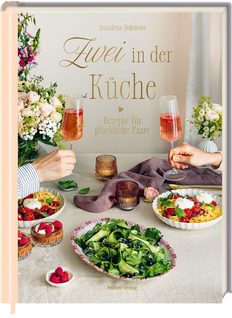 „Zwei in der Küche: Rezepte für glückliche Paare“. Zwei Personen stoßen mit Sekt an, umgeben von Blumen und Speisen.