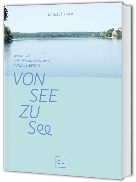 "Daniela Bialk. Wandern auf dem 66-Seen-Weg rund um Berlin. VON SEE ZU See. See mit Bäumen und Gebäuden im Hintergrund."