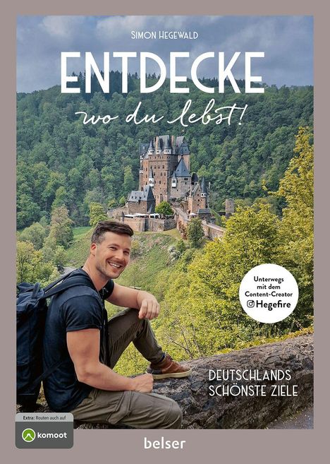 "Entdecke wo du lebst!" Ein lächelnder Mann sitzt vor einer historischen Burg inmitten eines grünen Waldes.