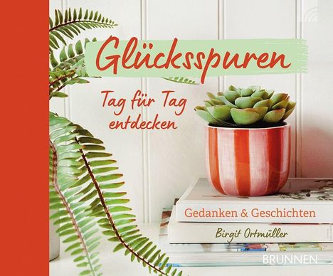 "Glücksspuren Tag für Tag entdecken" steht über einem Sukkulententopf und Büchern.