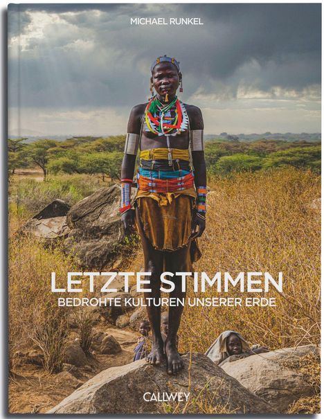 "LETZTE STIMMEN Bedrohte Kulturen unserer Erde." Ein farbenfroh gekleideter Mensch steht in einer trockenen Landschaft.