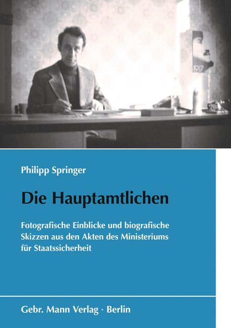 Text: "Philipp Springer. Die Hauptamtlichen. Fotografische Einblicke und biografische Skizzen. Gebr. Mann Verlag, Berlin." 
Ein unscharfes Foto eines Mannes am Schreibtisch.