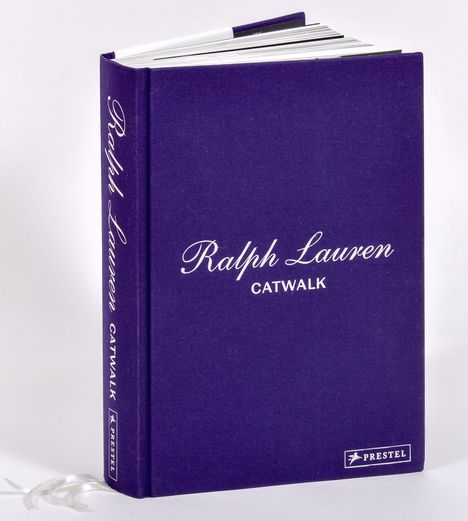 "Ralph Lauren CATWALK" in weißer Schrift auf dunkelviolettem Buch. Lesezeichen hängt heraus.