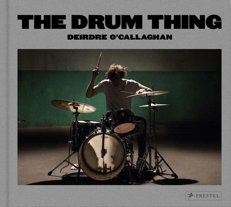 "The Drum Thing" oben, "Deirdre O’Callaghan" darunter. Ein Schlagzeuger spielt leidenschaftlich im Schatten.