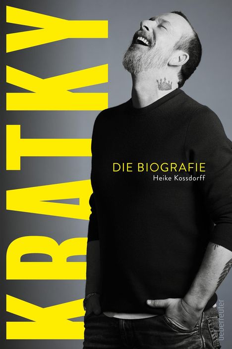 Gelber Text "KRATKY", darunter "DIE BIOGRAFIE" von Heike Kossdorff. Mann lacht, hat Bart und Krone-Tattoo am Hals.