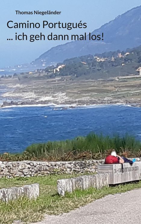 Text: "Thomas Niegeländer Camino Portugués ... ich geh dann mal los!" Küste mit Meer, grünes Gras und Bank im Vordergrund.