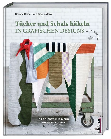 „Tücher und Schals häkeln in grafischen Designs.“ Bunte, grafisch gestaltete Häkelstücke hängen über einem Holzhocker.