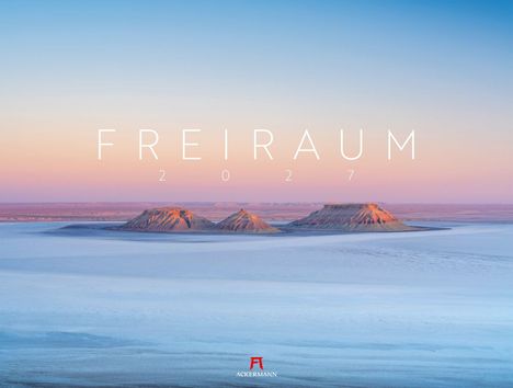 FREIRAUM 2027. Drei flache Berge erheben sich in einer weiten, offenen Landschaft unter einem klaren Himmel.