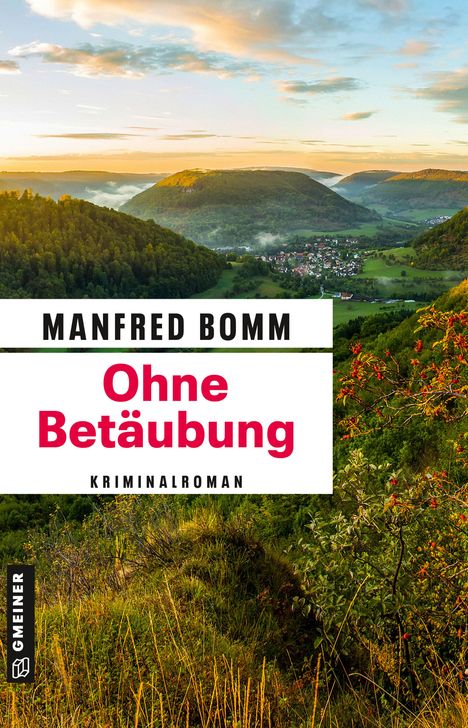 "Manfred Bomm, Ohne Betäubung, Kriminalroman." Landschaft mit Hügeln, Wald und einem Dorf im Tal bei Sonnenuntergang.