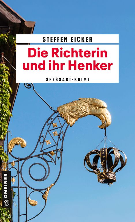 „Steffen Eicker: Die Richterin und ihr Henker.“ Ein kunstvoller, goldener Adlerkopf und eine Krone hängen an einer Schmiedearbeit.